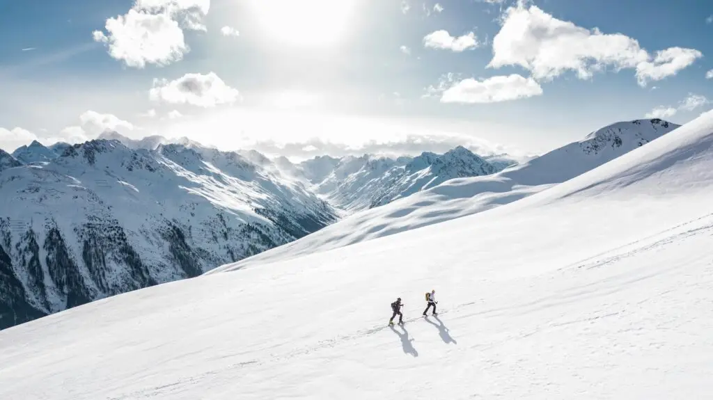 Sustainable Skiing ski tourers walking up the piste in the snowy mountains