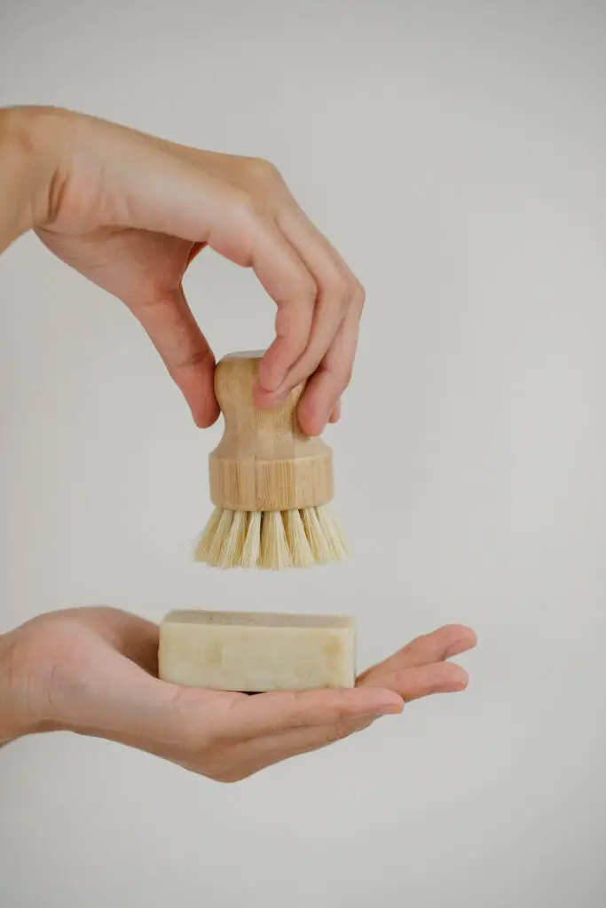 Lady holding a natural body brush and natural eco friendly soap between her hands to demonstrate sustainable beauty.