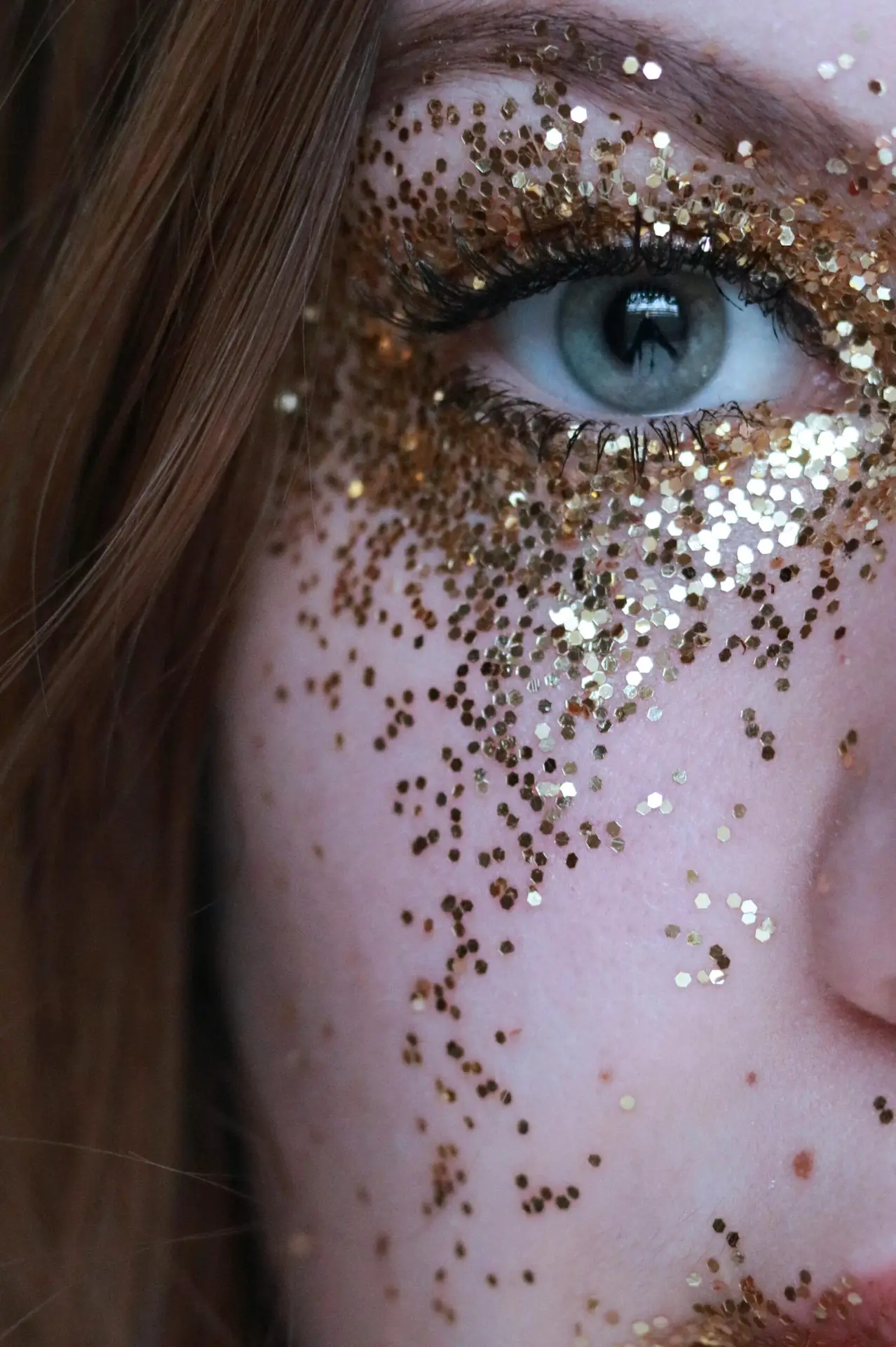 Woman with gold glitter on her face around one eye. Showing Eco glitter which is 100% biodegradable.